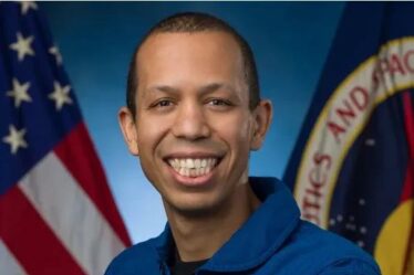 man poses with American flag and NASA flag in background