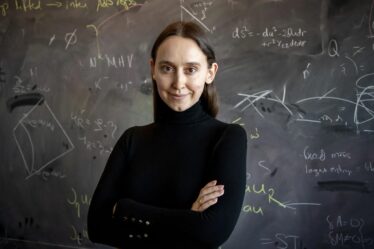 woman poses in front of blackboard