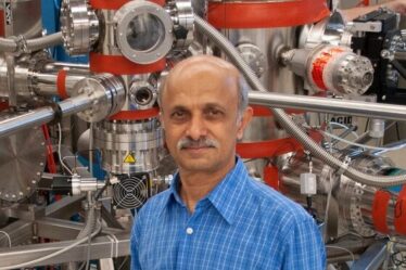 Senior Research Scientist Jagadeesh Moodera poses in front of a molecular beam epitaxy system