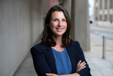 Woman smiles and poses with arms crossed