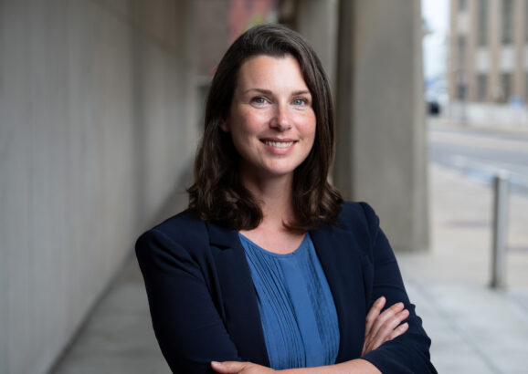 Woman smiles and poses with arms crossed