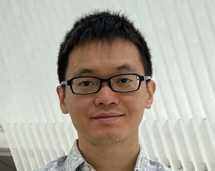 headshot of man in glasses standing in front of white diagonal slats