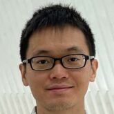 headshot of man in glasses standing in front of white diagonal slats
