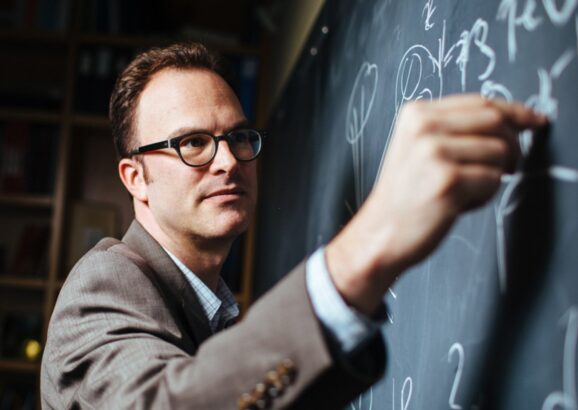 Jesse Thaler writes on a chalkboard